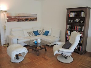 A living room with a white sofa, two armchairs, a coffee table, a bookshelf, and a painting on the wall. - La Quercia by Interhome (Ascona)
