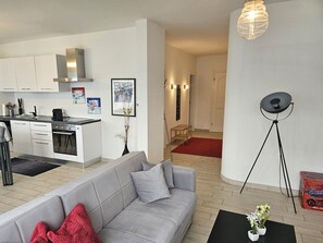 A modern living space with a grey sofa, a kitchen area, and a dining table. - Belinda by Interhome (Minusio)