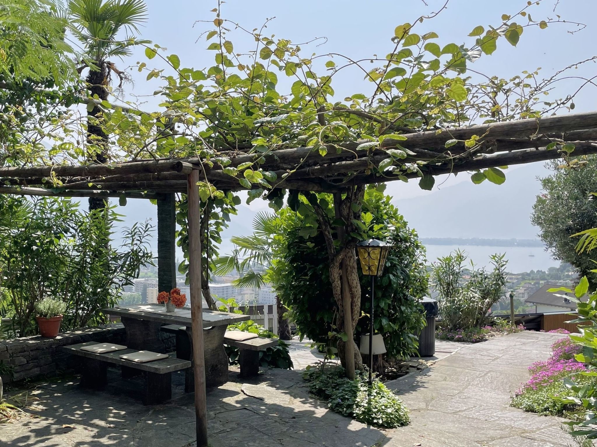 Un jardín con una pérgola, zona de estar y vista al mar.