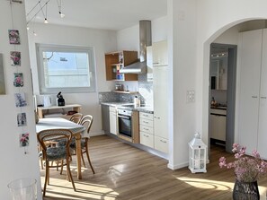 A modern kitchen with wooden cabinets, a built-in oven, and a dining area with a table and chairs. - Casa Rondinella by Interhome (Orselina)