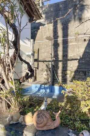 A garden area with a snail sculpture, a tree, and a concrete wall. - Casa Rondinella by Interhome (Orselina)