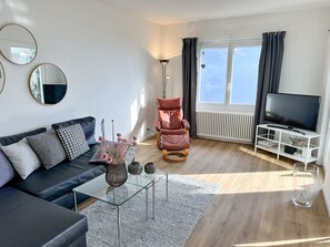 A modern living room with a sofa, a red recliner, a glass coffee table, and a TV. - Casa Rondinella by Interhome (Orselina)