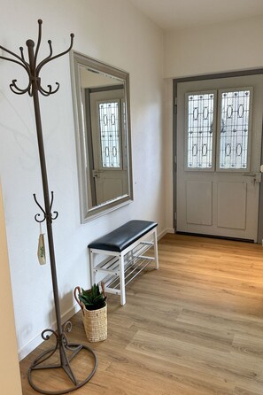 A hallway with a coat rack, bench, and a door with frosted glass panels. - Casa Rondinella by Interhome (Orselina)