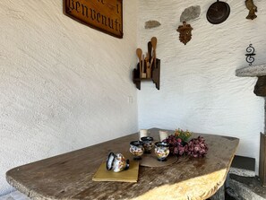 A rustic wooden table with a vintage sign above, a wall-mounted clock, and a collection of wooden utensils. - Casa Makatea by Interhome (Brione sopra Minusio)