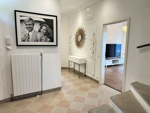 A modern interior with a framed photograph on the wall, a radiator, a white console table, and a television in a room. - Villa Grande Dame by Interhome (Minusio)