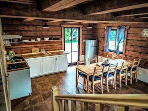 Ein rustikales Blockhaus-Interieur mit Küche, Essbereich und Blick ins Freie.