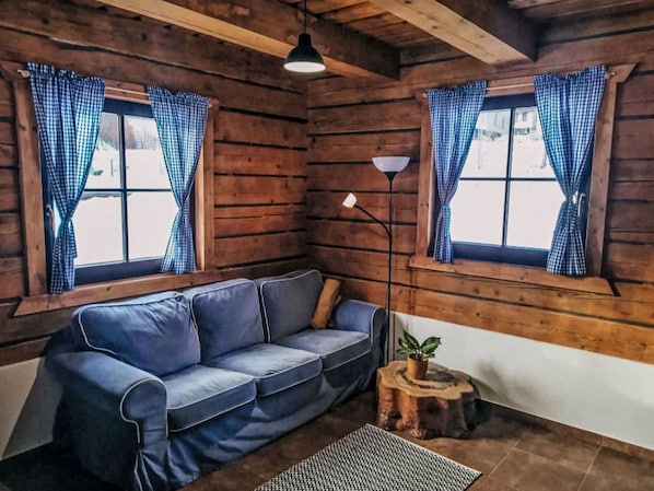 A cozy room with a blue sofa, a floor lamp, and checkered curtains.
