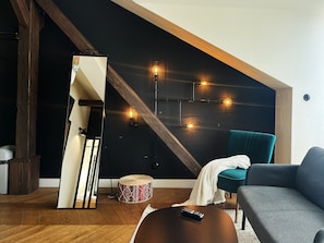 Ein modernes Wohnzimmer mit Holzboden, einer Couch, einem Couchtisch und einer Wandleuchte.