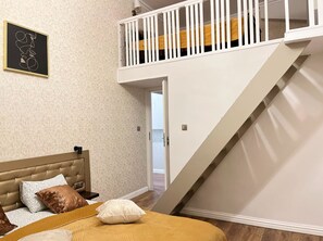 A bedroom with a bed, a nightstand, a wall-mounted picture, and a staircase. - Apartment for 8 guests in Jewish Disctrict Cracow, Bożego Ciała (Kraków)