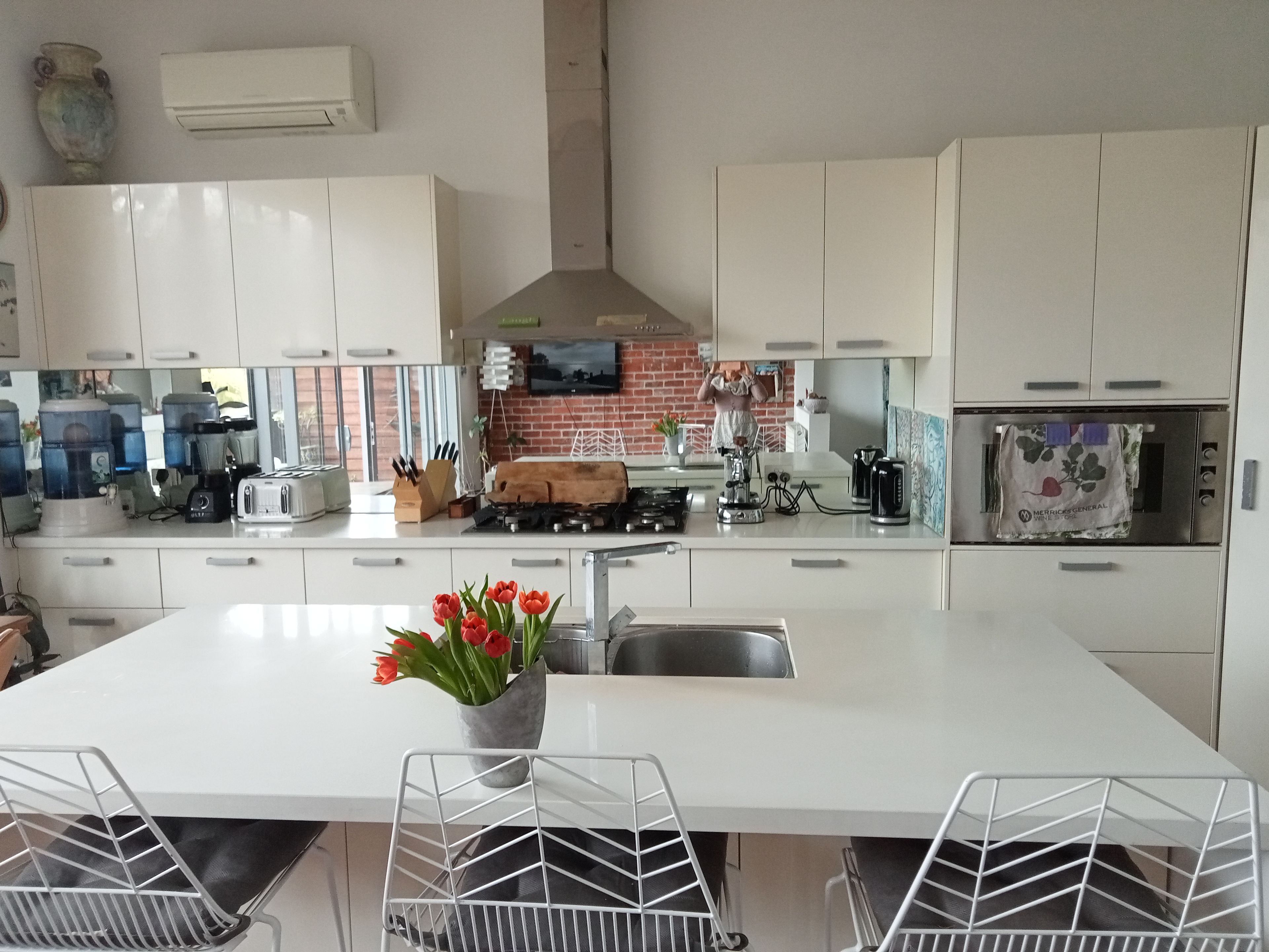 A modern kitchen with white cabinets, a central island with a sink, a gas stove, and a built-in oven.
