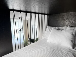 A bedroom with a bed, white bedding, a black metal headboard, and a view of a balcony with plants. - Premium Apartment for 3 guest with A/C in Cracow, Dąbrowskiego (Kraków)