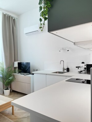 A modern kitchen with a flat-screen TV, a coffee machine, and a sink. - Premium Apartment for 3 guest with A/C in Cracow, Dąbrowskiego (Kraków)