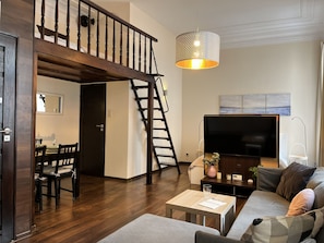 A modern living room with a staircase, a flat-screen TV, and a dining area. - Beautiful Studio for 4 guests, Main Square, Cracow, Marka (Kraków)