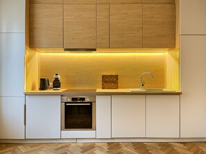 Eine moderne Küche mit eingebauten Geräten, einer Holz-Spritzschutzwand und einem Fischgrätenparkettboden.