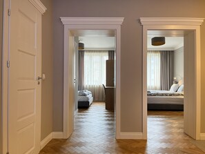 A hotel corridor with a wooden herringbone floor, a bed with a headboard and pillows, and a wardrobe. - 3-room Premium Apartment for 6 guests city center, Beliny Prażmowskiego (Kraków)
