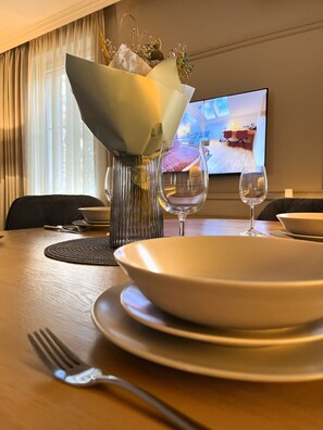 A dining table set with a vase of flowers, two wine glasses, and a bowl. - 3-room Premium Apartment for 6 guests city center, Beliny Prażmowskiego (Kraków)