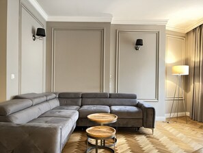 A modern living room with a sectional sofa, two round wooden tables, and a floor lamp. - 3-room Premium Apartment for 6 guests city center, Beliny Prażmowskiego (Kraków)