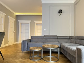 A modern living room with a sectional sofa, two round tables, and a wall-mounted lamp. - 3-room Premium Apartment for 6 guests city center, Beliny Prażmowskiego (Kraków)