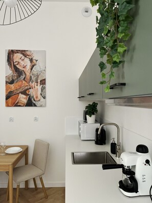 A modern kitchen with a microwave, coffee machine, and a potted plant. - Premium Apartament z AC, Cracow city center, Dąbrowskiego (Kraków)