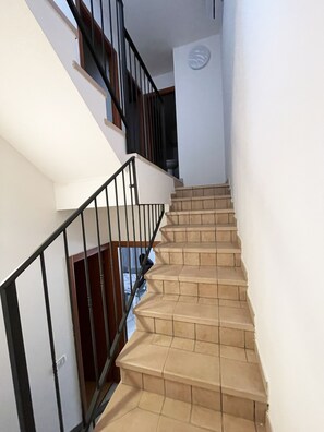 A staircase with beige tiles and black railings, leading to an upper floor. - Spacious Home With Pool and Terraces (Rosolina)