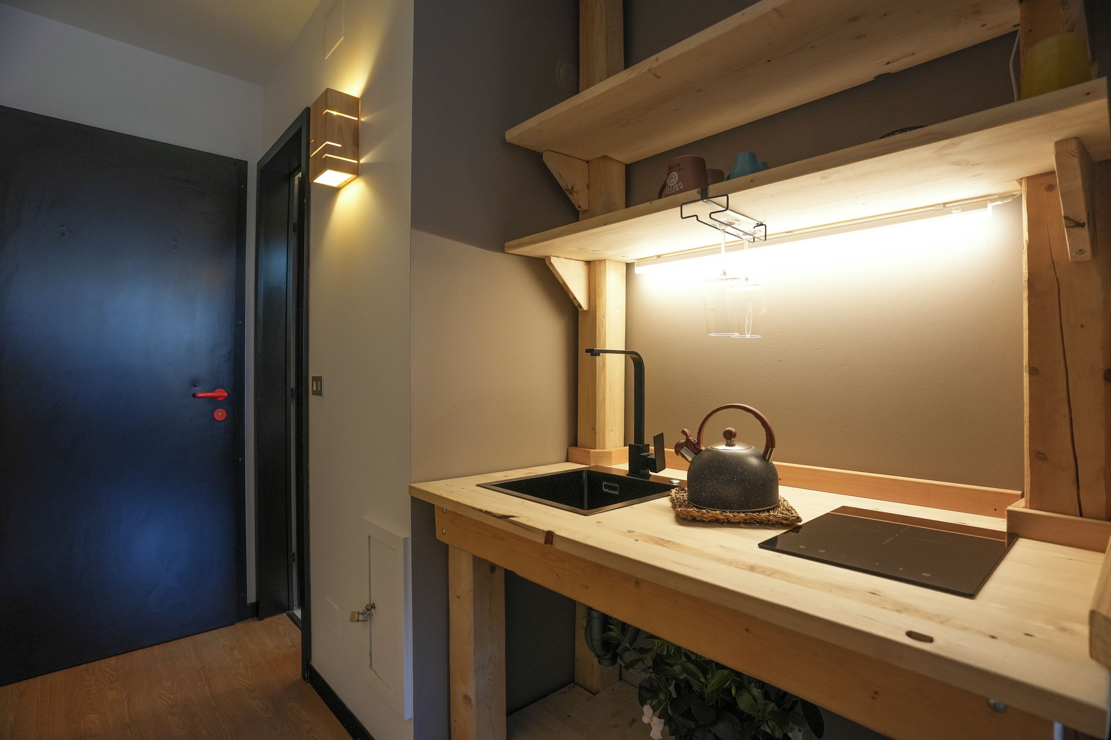 Una cocina compacta con encimera de madera, hervidor y estufa integrada.