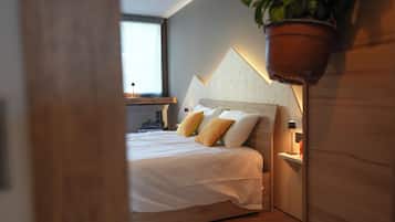 A bedroom with a bed, bedside lamps, a window, and a plant.
