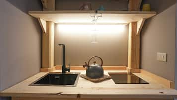 Una cucina compatta con un lavandino, un bollitore e un piccolo piano di lavoro.