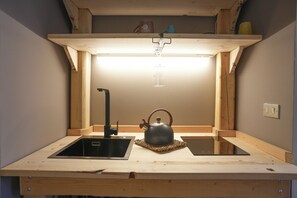 A compact kitchen with a single sink, a kettle, and a small countertop.