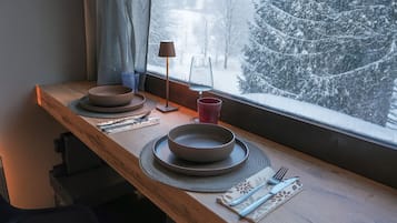 Un tavolo imbandito con piatti, posate e un bicchiere, vicino a una finestra con vista innevata.