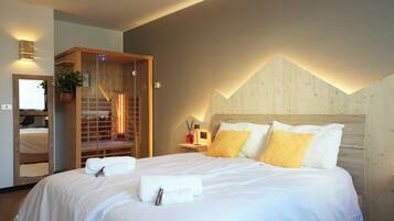 A hotel room with a large bed, a wooden headboard, a built-in sauna, and a mirror.