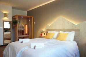 Ein Hotelzimmer mit einem großen Bett, einem Holz-Kopfteil, einer integrierten Sauna und einem Spiegel.