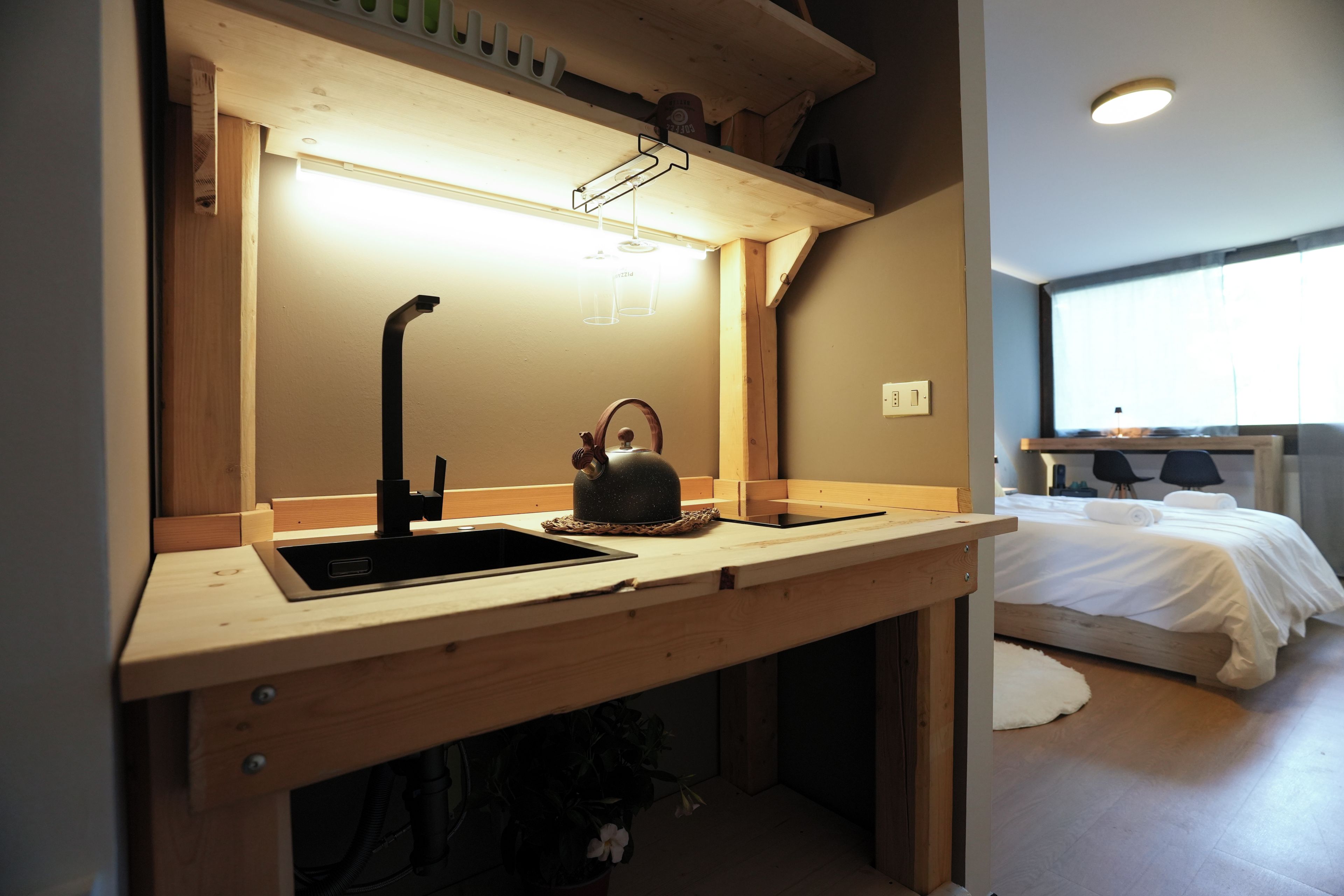 Eine moderne Küche mit einer Holz Arbeitsplatte, einem schwarzen Spülbecken und einem Wasserkocher.