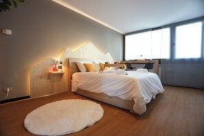 A modern bedroom with a wooden bed, a white rug, and a desk with a chair.