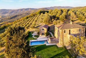 A stone villa with a swimming pool, surrounded by terraced vineyards and hills. - Villa la Cicogna pool and SPA - My Rental Homes (Montecolognola)