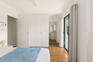 A bedroom with a bed, a nightstand, a window with curtains, and a hallway leading to a bathroom. - 3BR 2.5BA with private outdoor space (Sylvania)