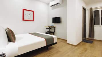 Habitación de hotel con cama, televisión de pantalla plana, aire acondicionado y un cuadro en la pared.