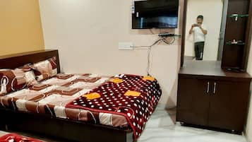 A hotel room with a bed, a TV mounted on the wall, a mirror, and a wardrobe.