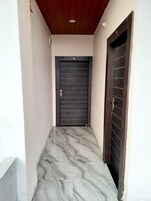 A hallway with a marble floor, a dark door with the number 2, and a wooden ceiling.