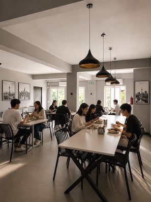A modern dining area with multiple tables and chairs, pendant lighting, and cityscape artwork on the walls. - Manzl Collective - Palm (Tada Khandrika)
