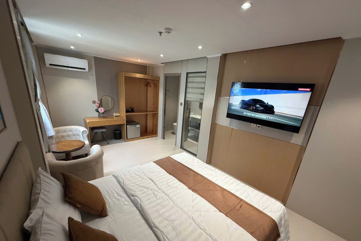Une chambre d’hôtel moderne avec un grand lit, un téléviseur fixé au mur, un bureau et une chaise.