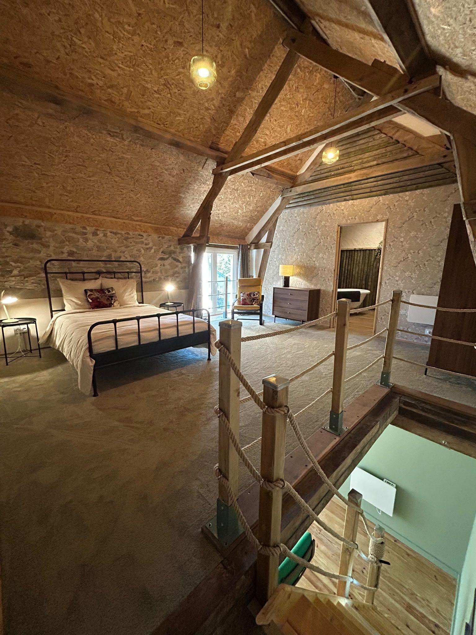 Een knus zolderkamer met een bed, een tafeltje en een stoel.