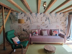 A living room with a green armchair, a pink sofa, and a wooden coffee table.
