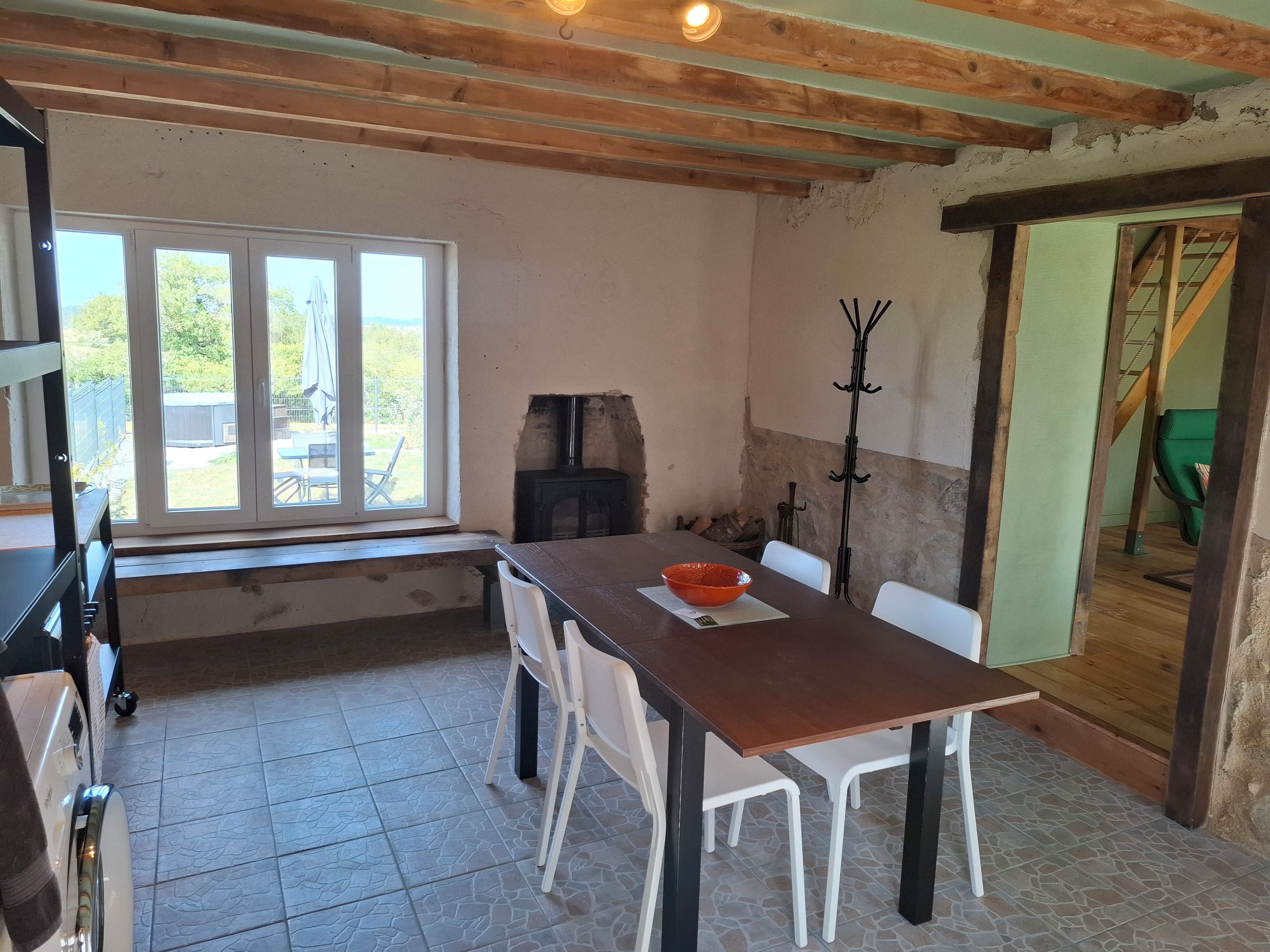 Een eethoek met een tafel, stoelen, een schaal, een open haard en een raam.