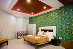 Una habitación de hotel con una cama, un armario, un banco y una pared estampada.