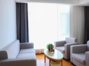 A living room with a sofa, armchairs, a coffee table, and a plant.