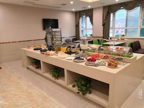 A buffet setup with various food items and a television screen on the wall. - Greentree Inn Fuyang Yingshang Yingyang Road Suzhou Manor Hotel (Fuyang)