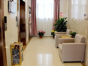 A hotel lobby with a reception desk, a trash bin, a seating area with sofas, and potted plants. - Greentree Inn Fuyang Yingshang Yingyang Road Suzhou Manor Hotel (Fuyang)