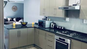 Una cocina moderna con electrodomésticos de acero inoxidable, armarios de colores claros y piso de baldosas.