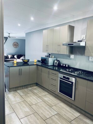 Cozinha moderna com eletrodomésticos de aço inoxidável, armários claros e piso revestido com azulejos.