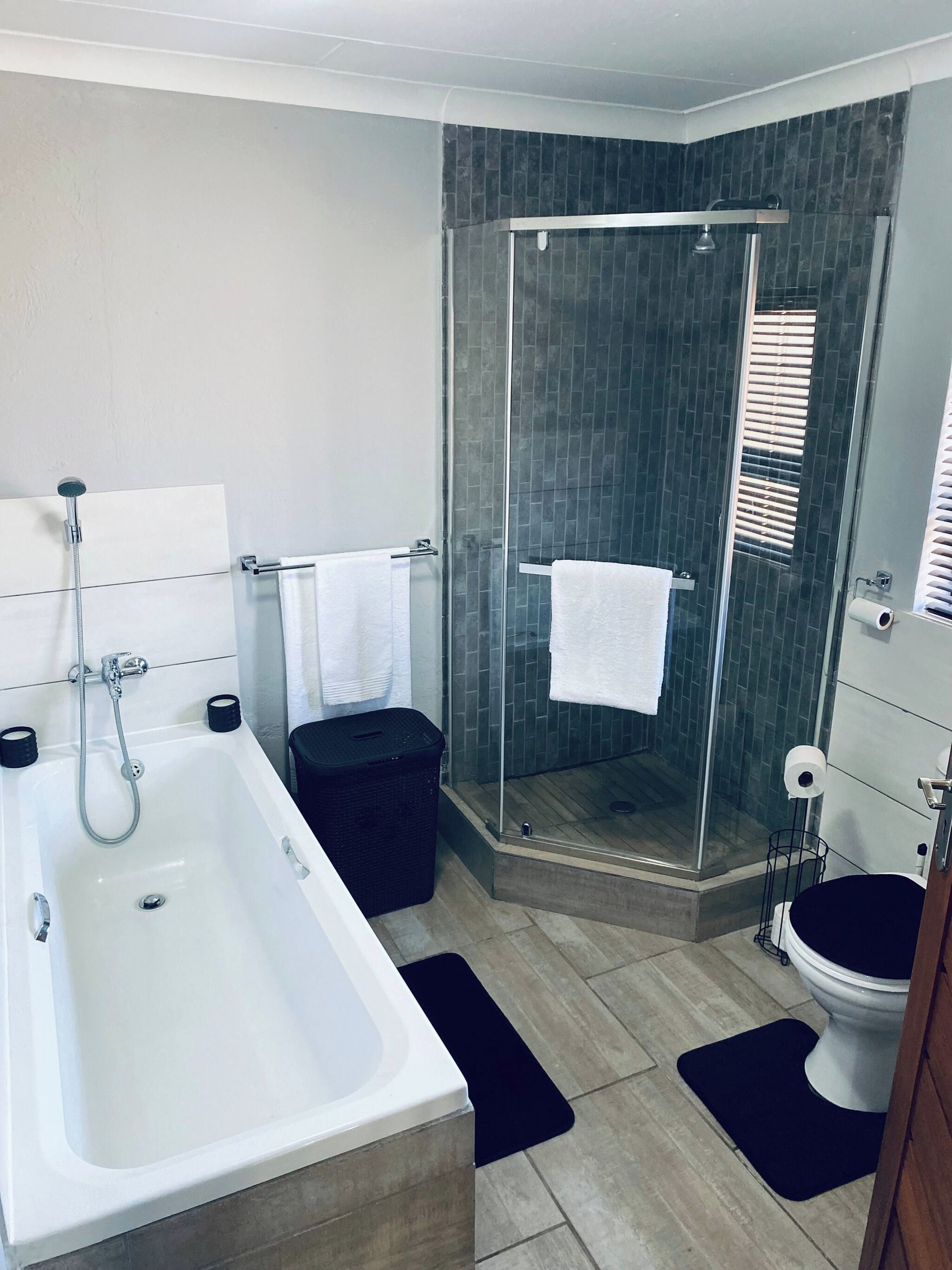 A modern bathroom with a bathtub, a glass-enclosed shower, and a toilet.
